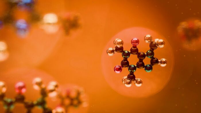 Molecular structure model with glowing atoms against an orange blurred background, illustrating complex chemical bonds.