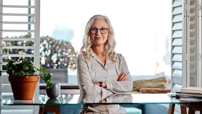 Confident woman sitting at desk with arms crossed, representing savage moments of literally owning the company in a business setting.