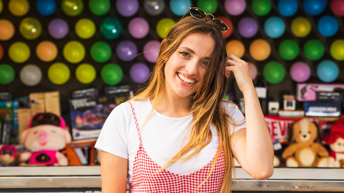 Young woman smiling confidently in front of colorful balloons, capturing savage I literally own the company moments.