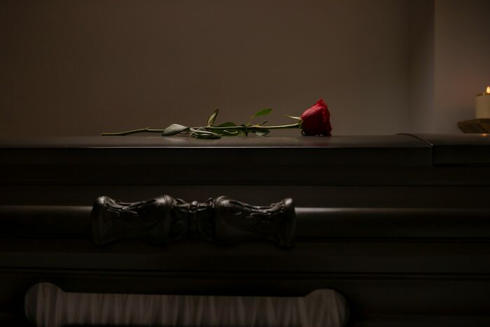 A single red rose on a dark wooden coffin in a dimly lit room, evoking terrifying moments for urban explorers.