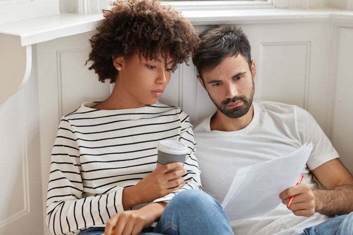 Woman and husband reading documents together, discussing family expectations about in-laws gifting money.