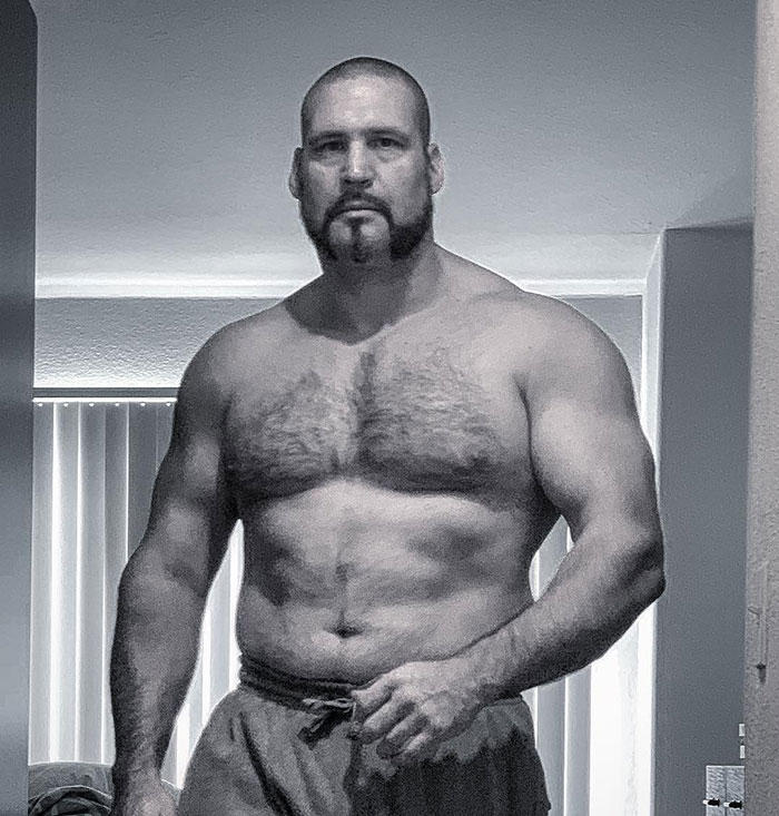 Muscular man with a beard posing shirtless indoors related to security guard identity controversy fans discuss. Muscular man with a beard posing shirtless indoors related to security guard identity controversy fans discuss.