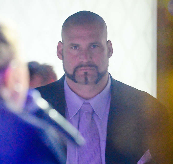 Security guard at the center of Chappell Roan and Jude Law's daughter's debacle wearing suit and tie in a dim setting