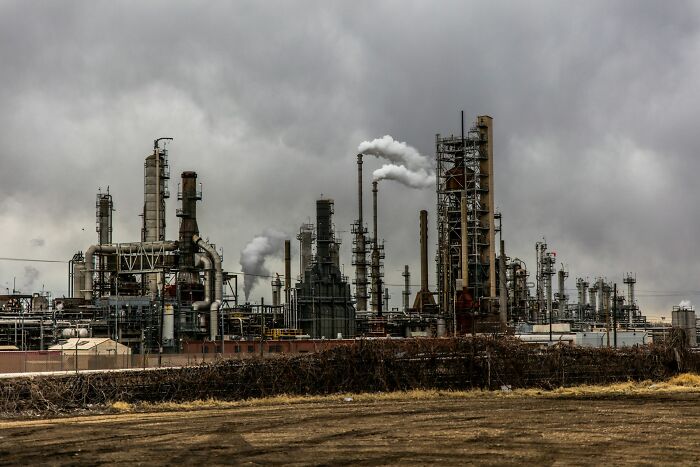 Industrial refinery complex emitting smoke under a cloudy sky, representing shaky industries at risk of collapse.