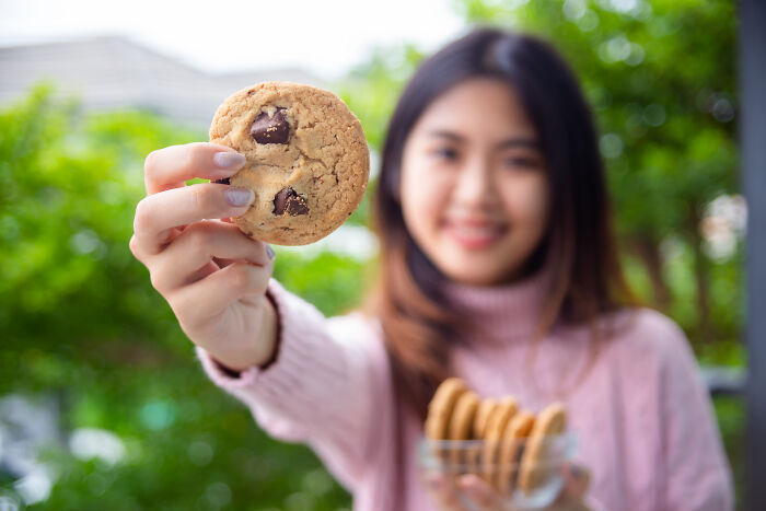 Young woman holding chocolate chip cookies, symbolizing old petty grudges people still have against strangers.