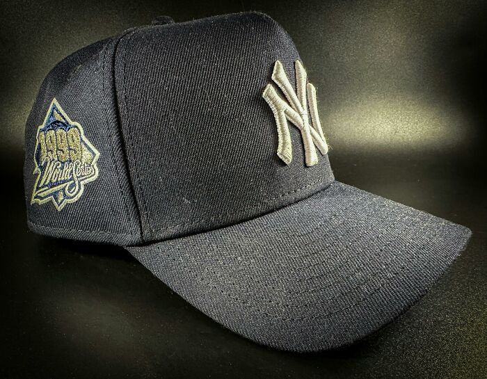 Dark navy baseball cap featuring a New York Yankees logo with a 1996 World Series patch on side against dark background.