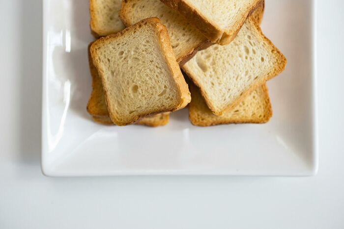 Several slices of toasted bread stacked on a white rectangular plate, highlighting simple food elements.
