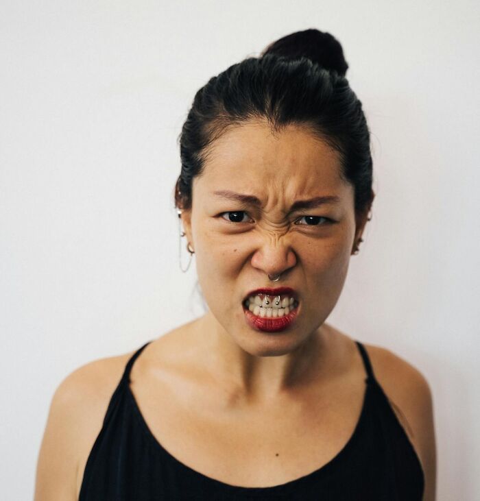Angry woman with piercings and red lipstick expressing frustration, illustrating women shutting down men’s creepy advances.