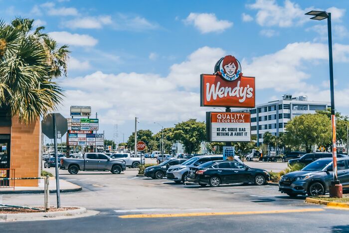 Wendy’s restaurant exterior with parking lot under blue sky, illustrating customers’ ridiculous complaints and employee reactions.
