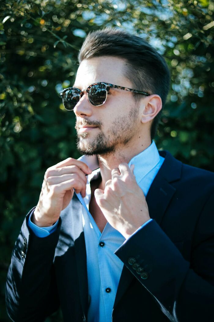 Young man wearing sunglasses adjusting collar outdoors, representing things people said that sounded like a complete joke but were serious.