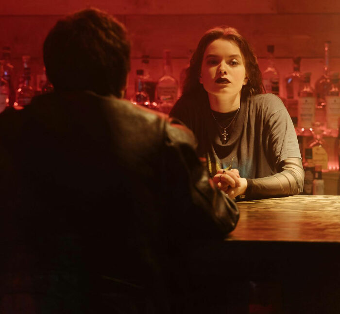 Two people having a tense conversation at a bar during one of the most disastrous first dates in dim red lighting.