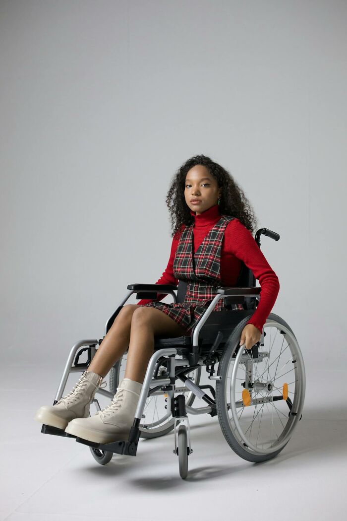 Young woman in wheelchair wearing red plaid dress and turtleneck, illustrating things people said that sounded like a complete joke but were serious.