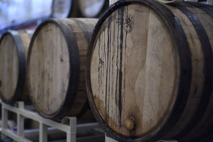 Wooden barrels lined up in a row inside a storage area, showcasing aged craftsmanship and rustic design.