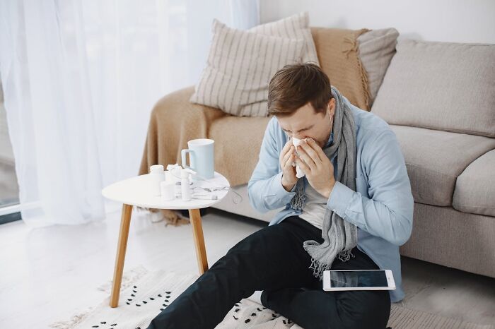 Young man with cold tissues and medicine, sitting on the floor, illustrating disastrous first dates and dating challenges.