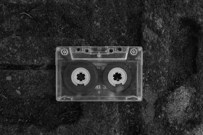 Clear audio cassette tape on a dark textured surface representing 80s kid pop culture and retro music nostalgia.