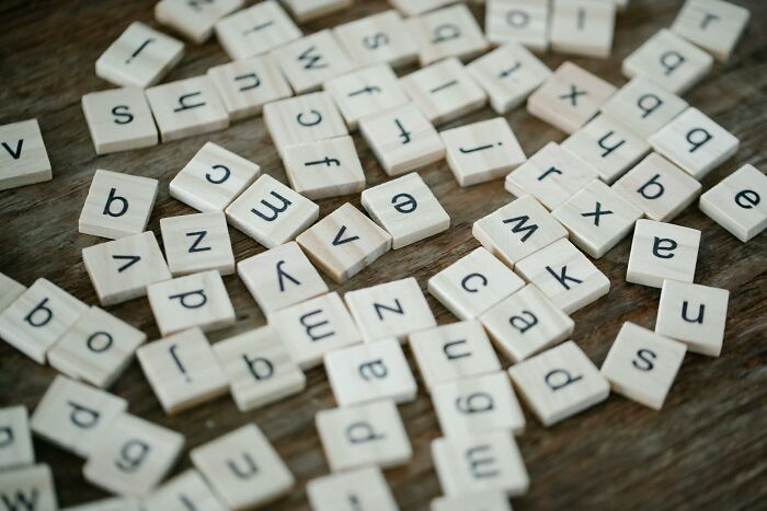 Scattered wooden letter tiles on a table representing brain-bending words to try unscrambling based on general knowledge facts.