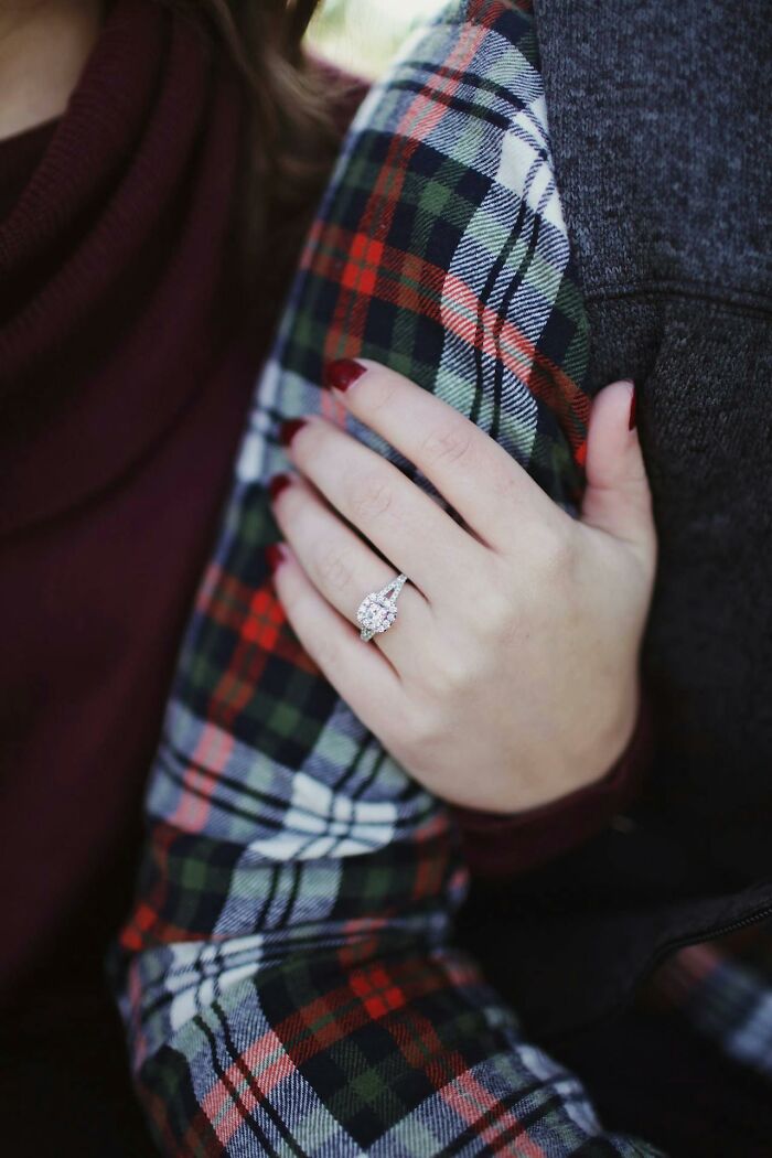Close-up of a hand wearing a sparkling engagement ring on a plaid shirt sleeve, symbolizing serious commitment despite sounding like a joke.