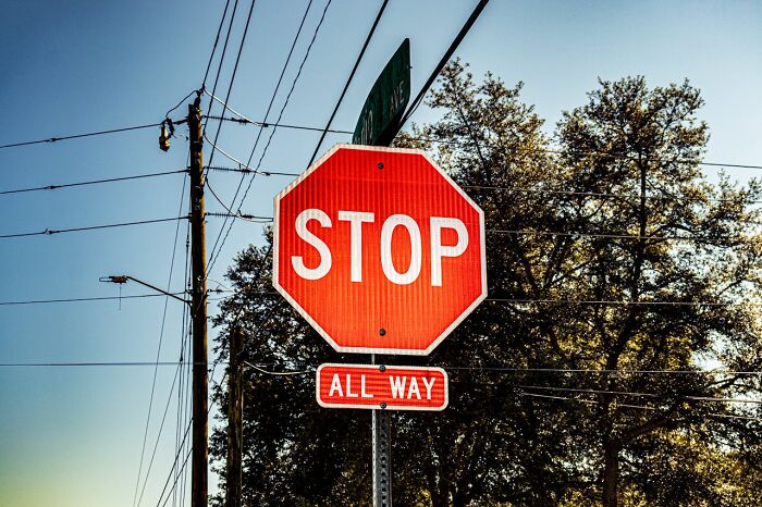 Stop sign on a pole with power lines and trees in background, illustrating challenges in ER medical staff experiences.