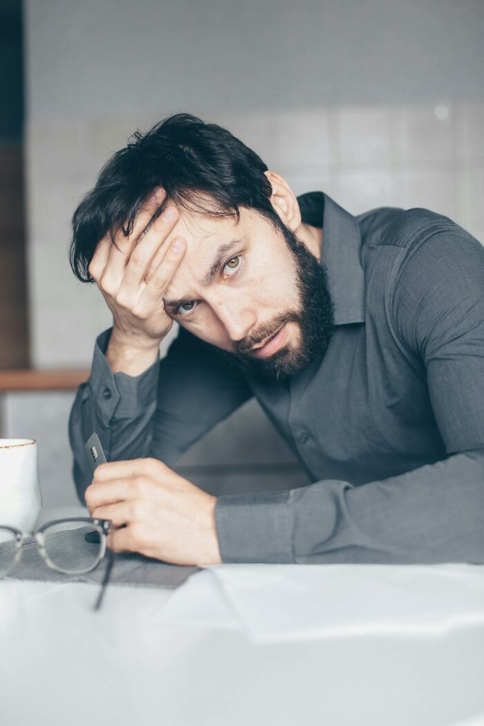 Bearded man in a gray shirt looking stressed while holding glasses, illustrating things people said that sounded like a joke
