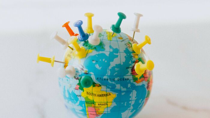 Globe with colorful push pins marking countries representing first achievements in history quiz about countries.