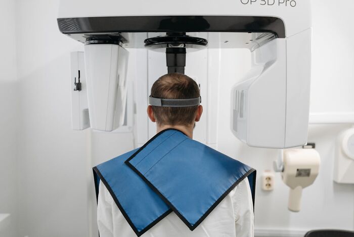Person undergoing a 3D dental scan wearing protective lead apron in a clinical setting related to serious statements that sounded like a joke.