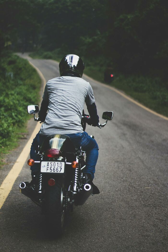 Motorcyclist riding on a winding road surrounded by greenery, illustrating hazards medical staff saw in the ER.