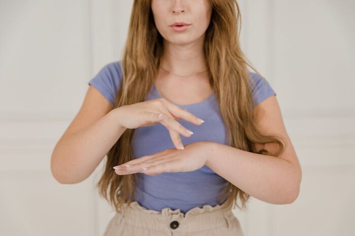 Woman in a purple shirt showing a stop gesture with her hands to shut down men’s creepy advances confidently.