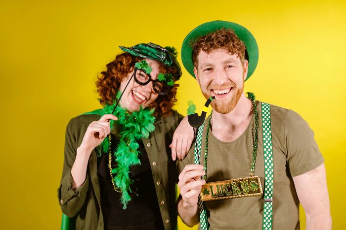 Two cheerful people dressed in St. Patrick’s Day accessories, symbolizing vanishing cultural truths in home countries.