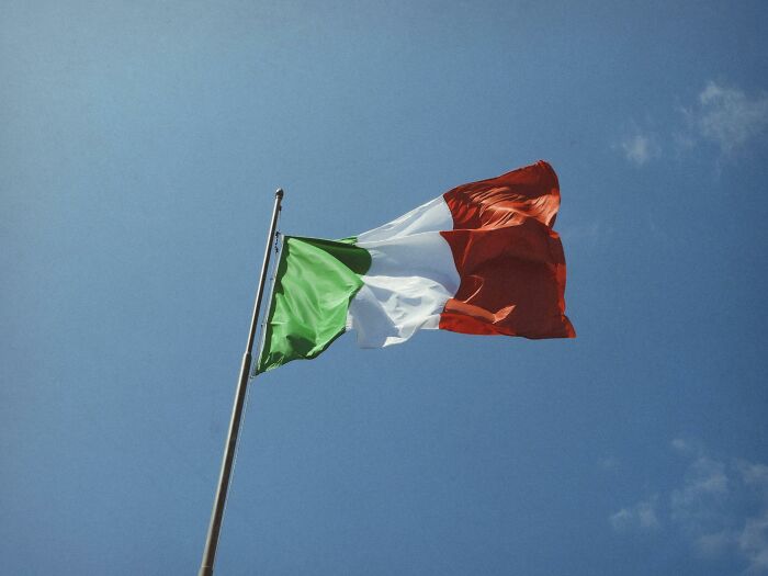Italian flag waving on a pole against a clear blue sky, illustrating unexpected customer complaints making employees laugh.