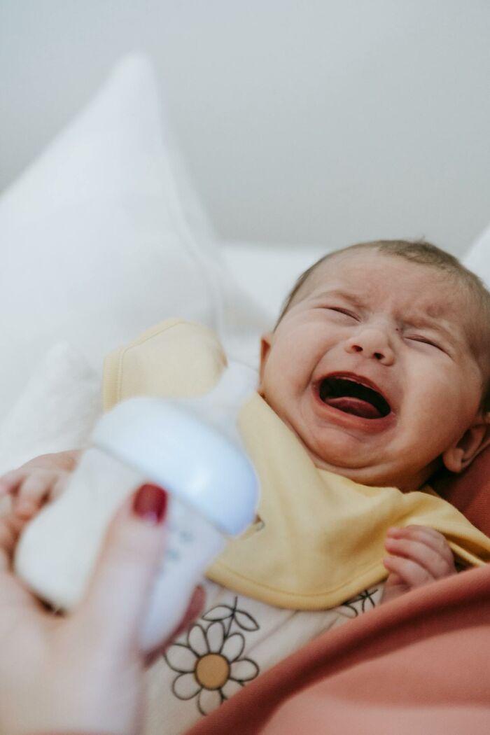 Crying baby in an ER setting being comforted by medical staff during a stressful emergency room situation.