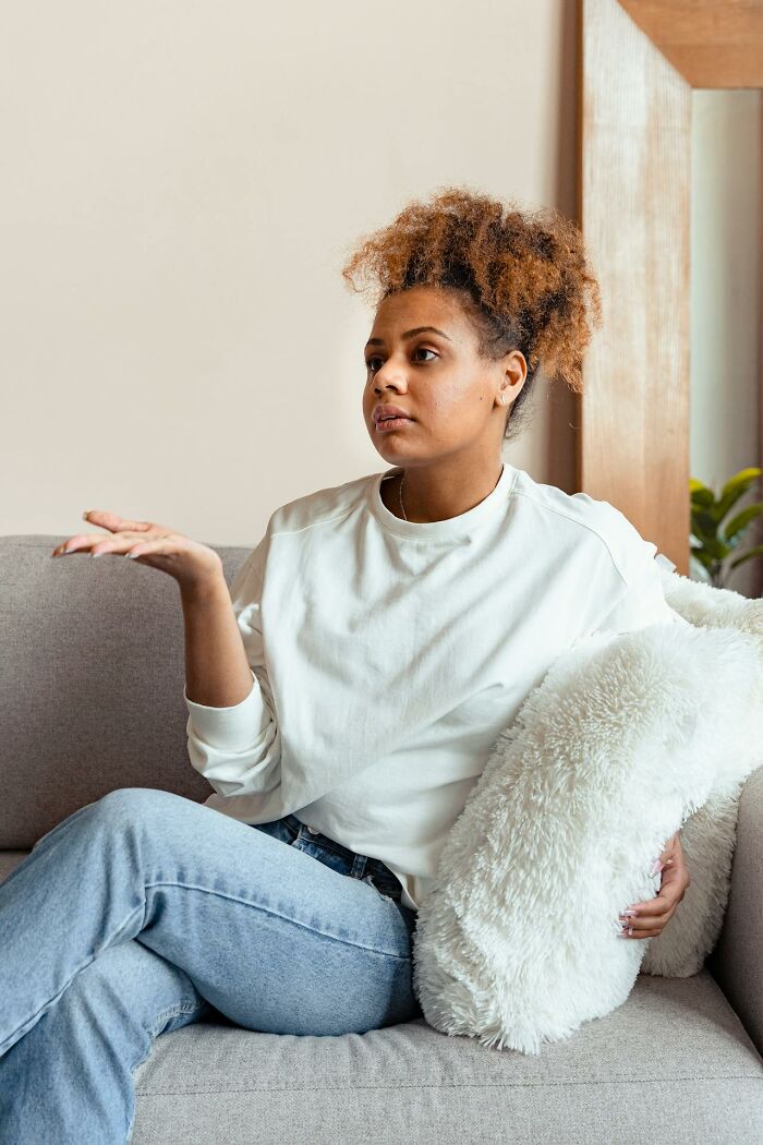 Woman sitting on couch looking serious and confused holding a fluffy pillow representing things people said that sounded like a joke