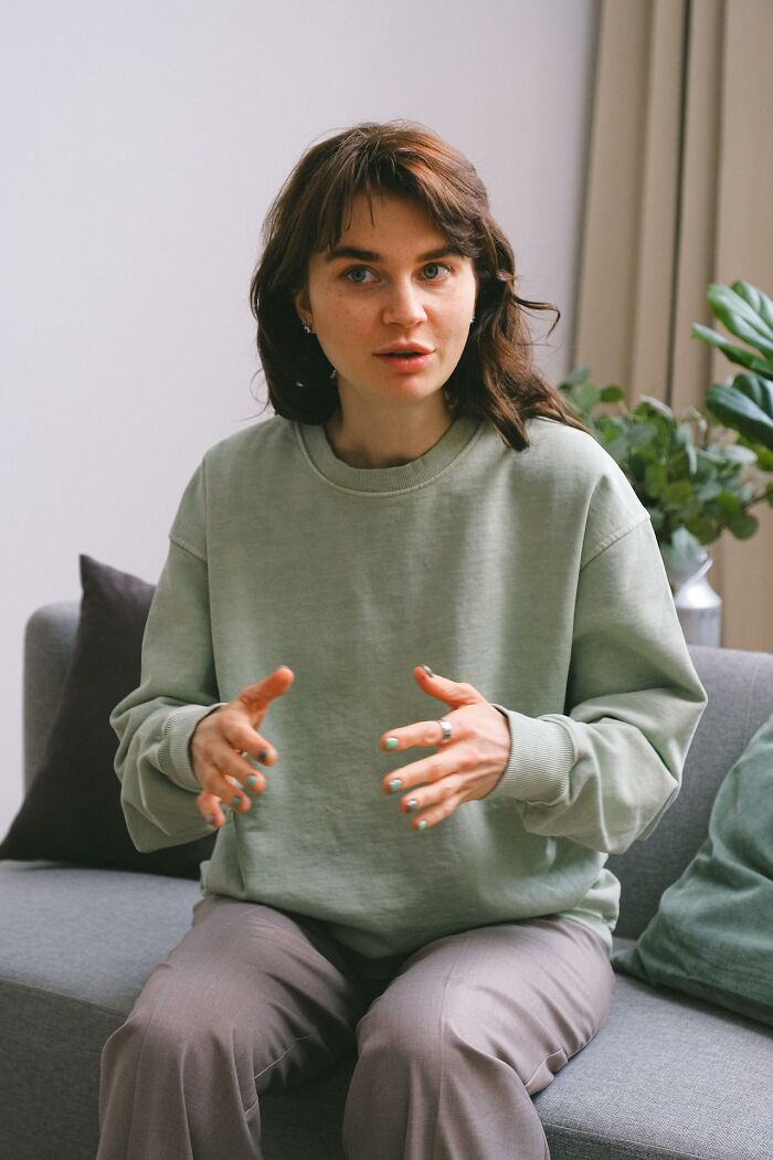 Young woman in a green sweatshirt explaining something seriously, illustrating things people said that sounded like a joke.