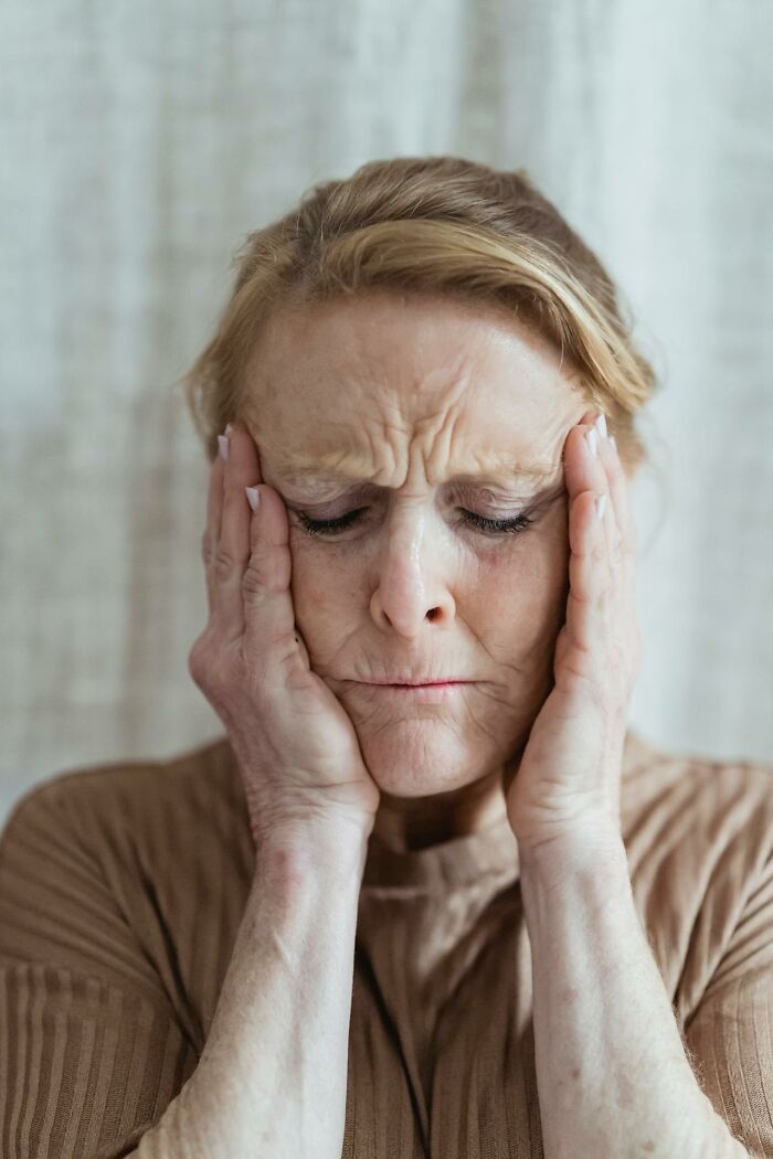 Stressed elderly woman holding her head, reflecting the toll on medical staff in the ER from horrible situations they witnessed.