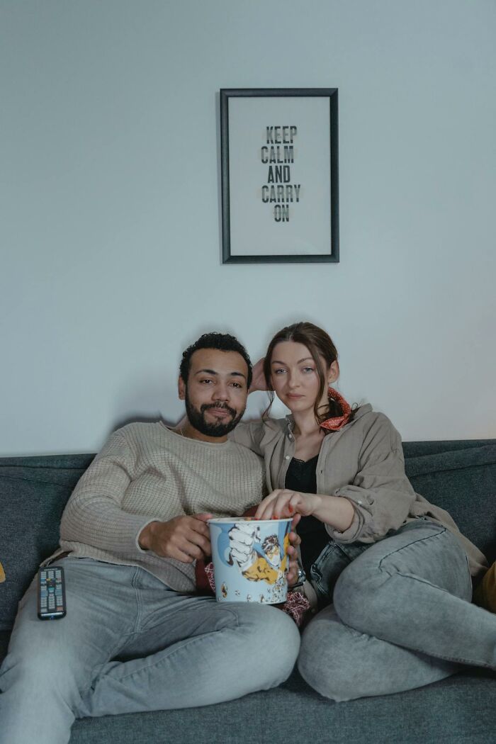 Couple sitting on a couch sharing popcorn during a relaxed moment, illustrating disastrous first dates and dating challenges.