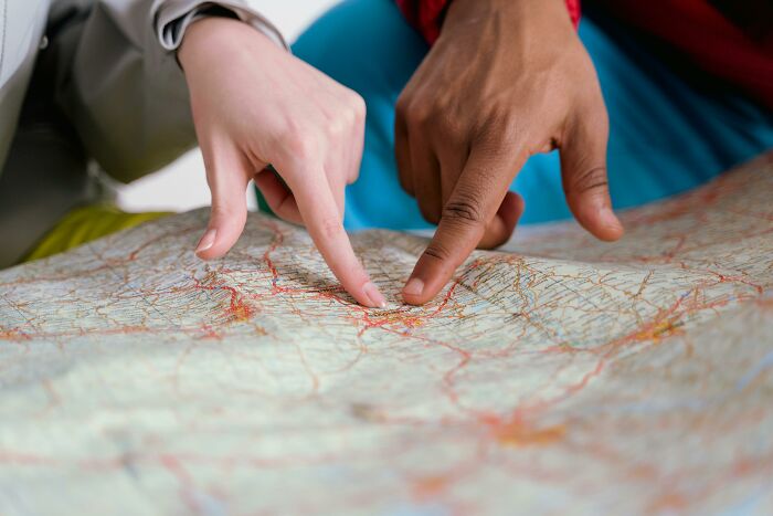 Two hands pointing at different locations on a detailed map, engaging geography fans in naming countries.