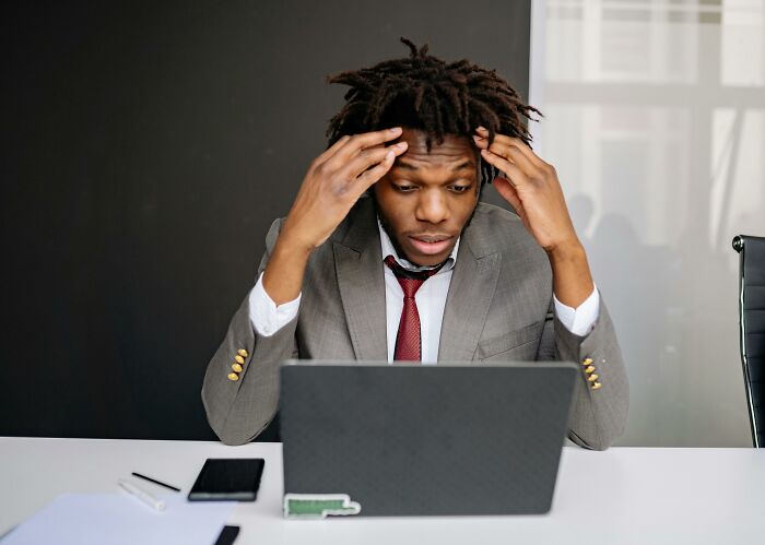 Man in a suit concentrating on a language, math, and visual pattern test on his laptop at a white desk.