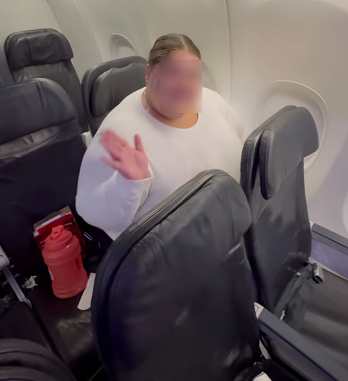 Passageiro afetado pela política de tamanho de novos clientes da companhia aérea sentado em um assento de avião, acenando com uma garrafa de água próxima.