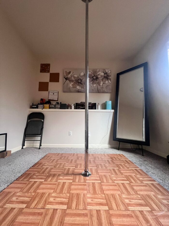 Home room with a dance pole on wooden floor and mirror, showing weird and unhinged family traditions in a casual setting.