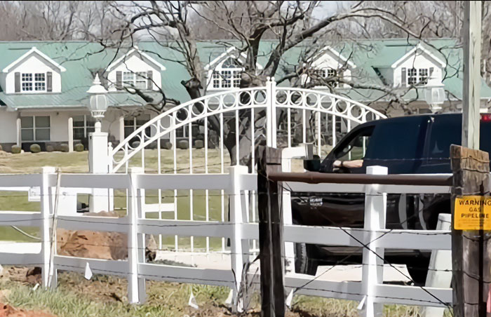 Rural neighborhood near Duggar family home with white fences and a black truck parked by the gate.