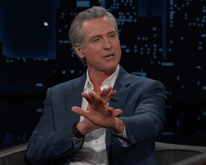 Man in a blue suit jacket making hand movements during a nighttime interview sparking concern about behavior.