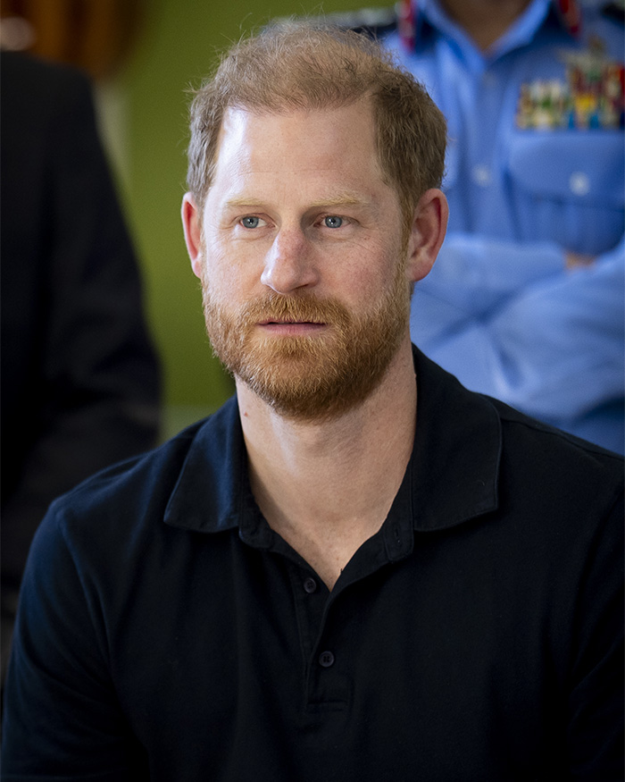 Prince Harry with concerned expression during emotional meeting, sparking attention to hand movements and behavior.