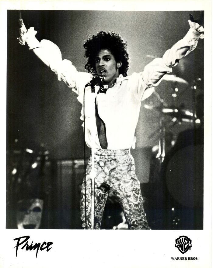 Black and white photo of a performer on stage with arms raised, highlighting celebrity custom $2.5 million mobile mansion.