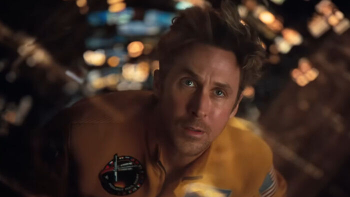 Ryan Gosling in an astronaut suit, portraying a scene from Project Hail Mary with a futuristic blurred background.