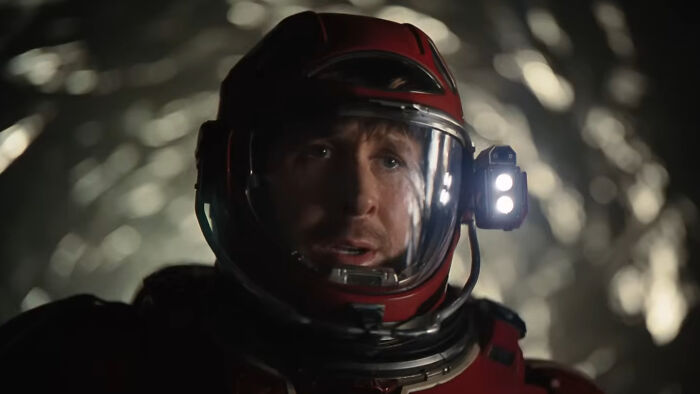 Ryan Gosling in a red space suit helmet, portraying a character in Project Hail Mary with a focused expression.