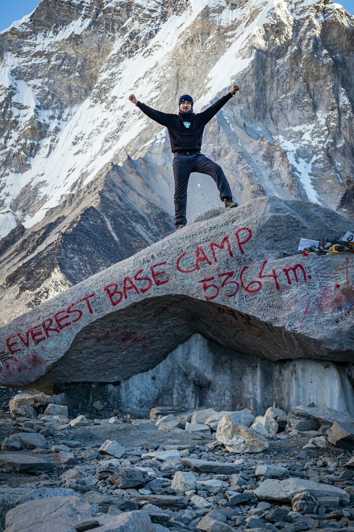 Person standing triumphantly on Everest Base Camp rock, illustrating moments people destroyed their own lives in an instant.