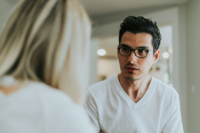 Man wearing glasses and a white shirt looking concerned during an intimate conversation about popping the question.