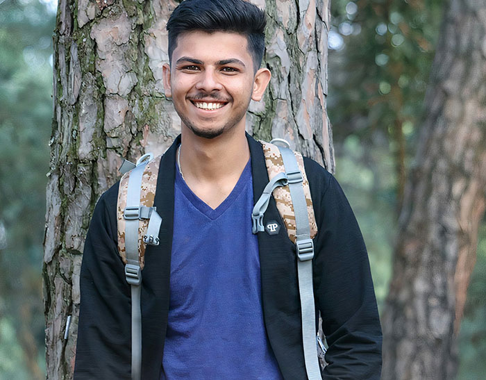 Young man smiling outdoors with backpack, illustrating moments people had to put the ring back during proposals.