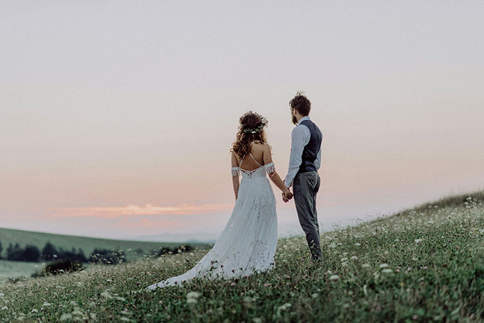 Couple holding hands in a field at sunset, symbolizing moments when people popped the question and faced embarrassment.