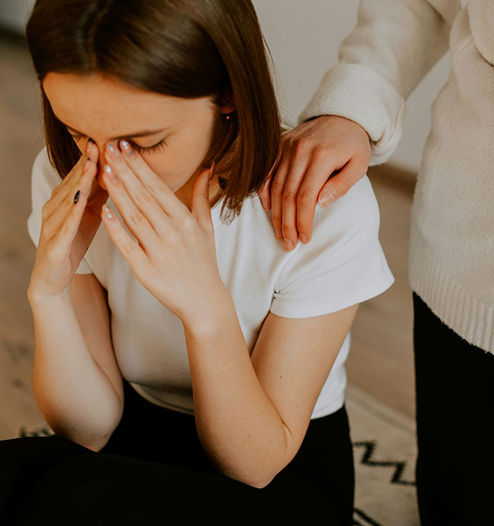 Woman upset after a proposal with a supportive hand on her shoulder, illustrating engagement ring embarrassment moments.