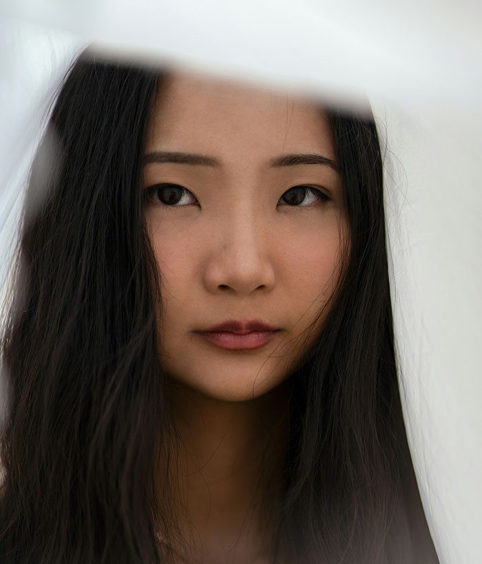 Close-up portrait of a woman with long dark hair looking thoughtful, capturing emotions tied to popped the question moments.